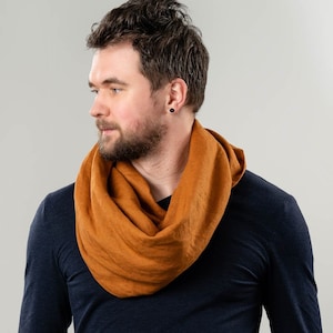 May include: A man wearing a dark blue long-sleeved shirt with a rust-coloured linen infinity scarf.