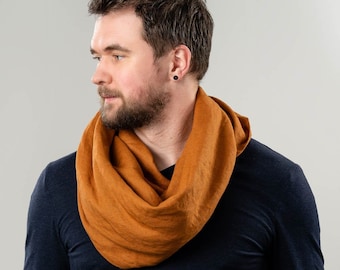 May include: A man wearing a dark blue long-sleeved shirt with a rust-colored linen infinity scarf.