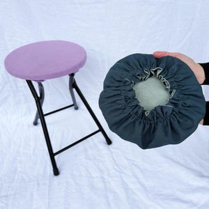 May include: A purple fabric covered folding stool with a black metal frame. A dark blue fabric cover with a white trim is shown separately.