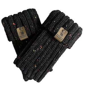 May include: A pair of black knitted wrist warmers with colorful flecks. Each warmer has a small, tan leather tag with the text "Handmade by Ladybugknitz" and a yarn and needle logo.