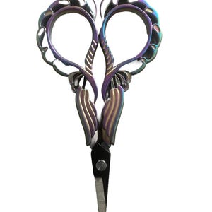 May include: Iridescent embroidery scissors with a decorative design. The scissors have a black blade and a colorful, ornate handle with a swirling pattern. The handles are shaped to fit the fingers, and the blades are sharp.