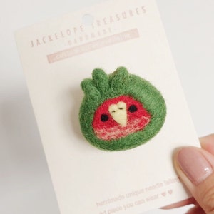 May include: A green felt pin with a red and yellow bird design. The pin is handmade and says "Jackelope Treasures Handmade" on the card.