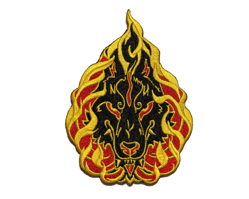 May include: Embroidered patch featuring a black wolf's head engulfed in flames. The flames are outlined in gold with red accents, creating a striking contrast against the black wolf. The patch is designed with intricate details.
