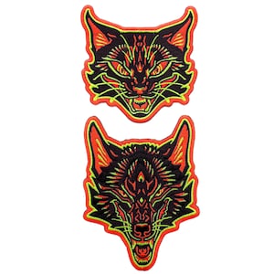 May include: Two iron-on patches featuring black and green animal faces with red outlines. The top patch is a cat face and the bottom patch is a wolf face.