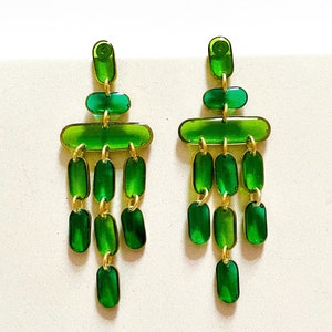 May include: A pair of green and gold chandelier earrings with multiple tiers of oval-shaped beads.