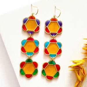 May include: A white ceramic mug with a black handle and the text "But First, Coffee" in a bold, black font. The mug is set against a blurred background, suggesting a cozy setting.