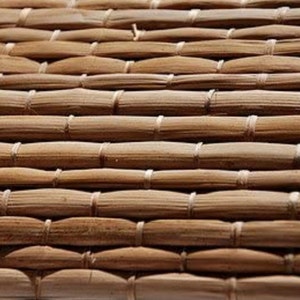 May include: Close-up of a woven brown mat made of natural materials. The mat has a textured surface and a natural, rustic look.