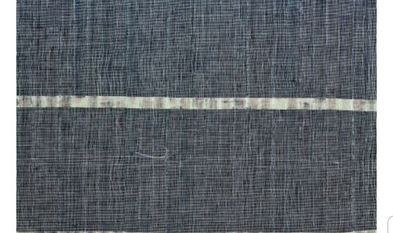 May include: Close-up of a textured fabric with a dark blue woven background. Two horizontal bands of off-white and light gray run across the fabric. The fabric has a slightly irregular weave, creating a subtle pattern.