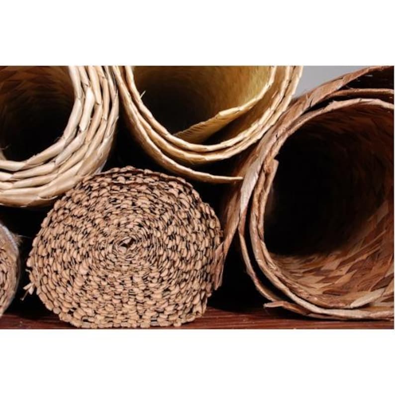 May include: Close-up of several rolls of natural woven material, likely for crafting or home decor. The rolls are made of different types of woven fibers, including a tightly woven brown roll and a lighter, more loosely woven roll.