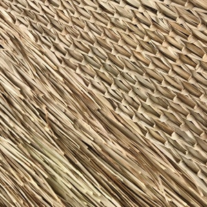 May include: Close-up of a woven mat made from natural fibers. The mat has a diagonal pattern and is made of light brown and beige strands.