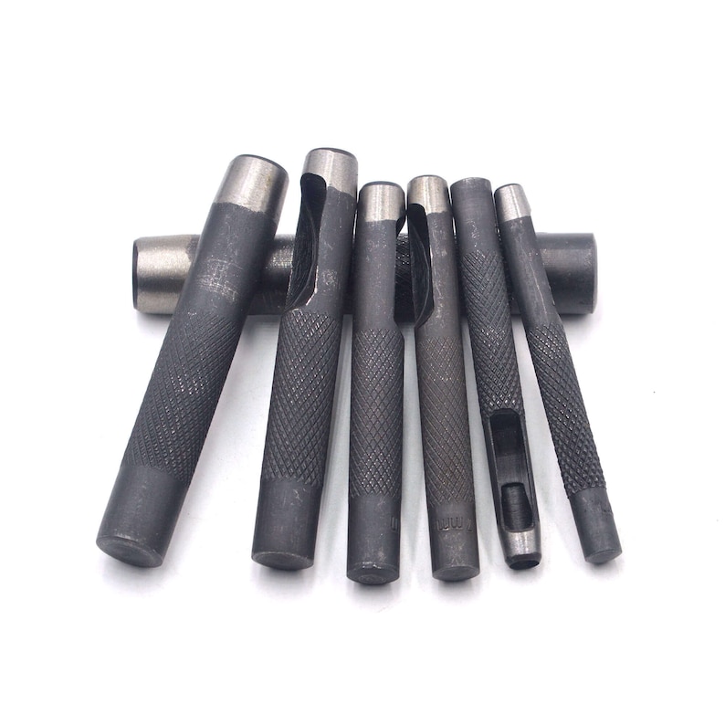May include: Set of eight metal leather hole punch tools with different sized holes. The tools are silver and have a textured grip.
