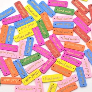 May include: Assortment of colorful wooden rectangular tags with the text "Hand made" in gold lettering. The tags are perfect for adding a handmade touch to crafts, gifts, and clothing.