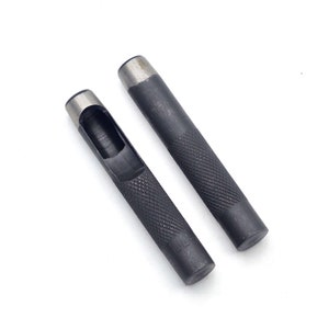 May include: Two black metal hole punch tools with a textured grip. The tools have a round hole punch at the top and a round handle.