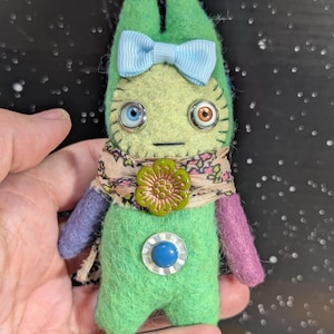 May include: A white ceramic mug with a black handle and the text "But First, Coffee" in a black, handwritten-style font. The mug is on a white surface.