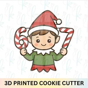 May include: A cartoon elf cookie cutter holding candy cane shaped numbers 6 and 7. The elf wears a red plaid hat, green shirt, and red trim. The text "3D PRINTED COOKIE CUTTER" is at the bottom.