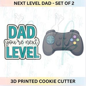 以下が含まれることがあります： 2つの3Dプリントクッキーカッターのセット。1つは、ターコイズと白で「DAD you're next LEVEL」と綴られています。もう1つは、カラフルなボタンが付いた灰色のビデオゲームコントローラーです。「NEXT LEVEL DAD - SET OF 2」と「3D PRINTED COOKIE CUTTER」の文字も表示されています。