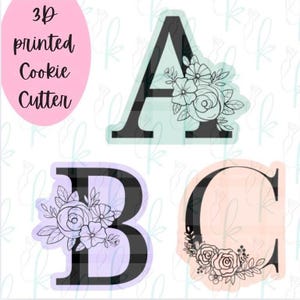 May include: 3D-printed cookie cutters in the shape of the letters A, B, and C, each adorned with floral designs. The letter A has a floral arrangement on the right side, while B and C have floral accents on the left and bottom, respectively. The text "3D printed Cookie Cutter" is on the left.