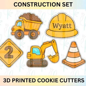 May include: A set of 3D printed cookie cutters with a construction theme. The set includes a dump truck, a hard hat with the name "Wyatt", a road sign with the number 2, an excavator, and a traffic cone. The text "CONSTRUCTION SET" and "3D PRINTED COOKIE CUTTERS" are also visible.