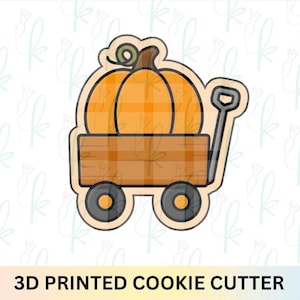 May include: A 3D printed cookie cutter shaped like a wooden wagon carrying a large orange pumpkin with a brown stem and a green vine. The wagon has a brown rectangular body, two black wheels with orange centers, and a black handle on the right side.