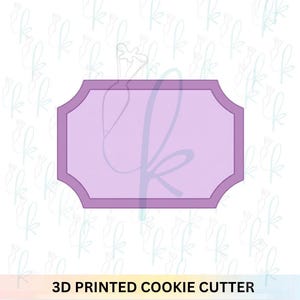 May include: A rectangular cookie cutter with decorative scalloped corners, featuring a light purple center and a darker purple border. The object has a flat, symmetrical shape with rounded edges, designed for cutting dough into a specific plaque form.