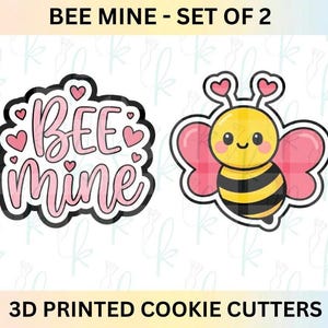 May include: Two 3D printed cookie cutters. One cutter spells "BEE Mine" in pink script with heart accents. The other is a cartoon bee with pink plaid wings and a smiling face. The text "BEE MINE - SET OF 2" is at the top.