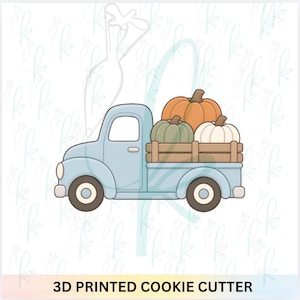 May include: A light blue pickup truck cookie cutter featuring a wooden truck bed filled with three pumpkins in orange, sage green, and white. The design includes a rounded cab, circular wheels, and the text 3D PRINTED COOKIE CUTTER at the bottom.