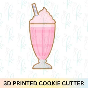 Peut inclure: Un emporte-pièce imprimé en 3D en forme de milkshake dans un grand verre avec une boisson rose, de la crème fouettée et une paille rayée bleue et blanche. Le texte 3D PRINTED COOKIE CUTTER est affiché au bas de l'image.