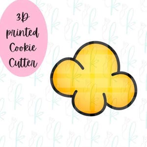 May include: A yellow popcorn-shaped cookie cutter with a thick black outline. The image features a pink oval containing the black text 3D printed Cookie Cutter, set against a white background with a repeating light blue logo pattern.