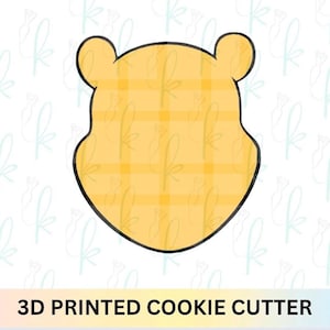 Könnte beinhalten: Gelber Ausstecher in Form eines Bärenkopfes mit Karomuster. Der Ausstecher hat eine schwarze Umrandung und den Text "3D PRINTED COOKIE CUTTER" unten.