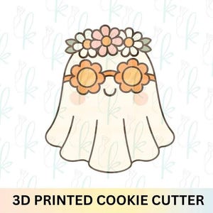 May include: A 3D printed cookie cutter featuring a cartoon ghost with a flower crown and flower-shaped sunglasses. The ghost is off-white with a smiling face and rosy cheeks. The text "3D PRINTED COOKIE CUTTER" is at the bottom.