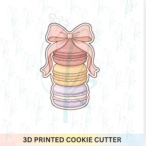 Puede incluir: Un cortador de galletas impreso en 3D con forma de pila de macarons, coronado con un lazo rosa. Los macarons son en tonos pastel de rosa, amarillo y lila. El texto "3D PRINTED COOKIE CUTTER" está en la parte inferior.