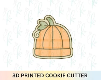 Puede incluir: Cortador de galletas impreso en 3D con forma de calabaza. La calabaza es naranja con hojas y un tallo verdes. El cortador tiene un contorno detallado y está diseñado para hacer galletas.
