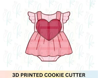 May include: A 3D printed cookie cutter shaped like a baby romper with ruffled sleeves and a large heart centered on the chest. The design features a light pink base color with a darker pink plaid pattern and a solid red heart in the middle.