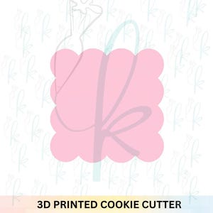 May include: A pink, scalloped-edge cookie cutter with a stylized design. The words "3D PRINTED COOKIE CUTTER" are printed in black at the bottom of the image. The background features a repeating pattern of light blue floral designs.