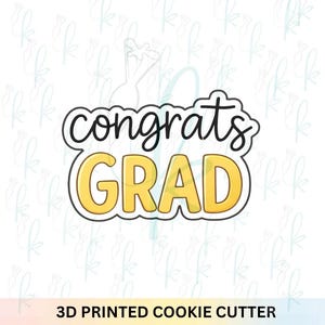 May include: A 3D printed cookie cutter with the words "congrats GRAD" in black and yellow. The word "congrats" is in a cursive font, and "GRAD" is in a bold, block letter font. The text is outlined in black.