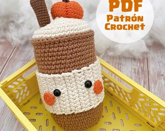 May include: Crochet pattern PDF for a brown and white crocheted pumpkin spice latte amigurumi. The amigurumi is sitting in a yellow plastic crate.
