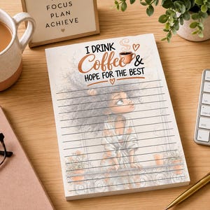 May include: A white notepad with black horizontal lines featuring an illustration of a person with voluminous hair looking up. The text reads I DRINK Coffee & HOPE FOR THE BEST with a small coffee cup icon and heart symbols above the lines.
