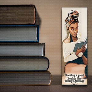 May include: A bookmark featuring an illustration of a woman reading a book, with a stack of books to the left. The woman is wearing a head wrap and gold hoop earrings. The text on the bookmark reads: "Reading a good book is like taking a journey."