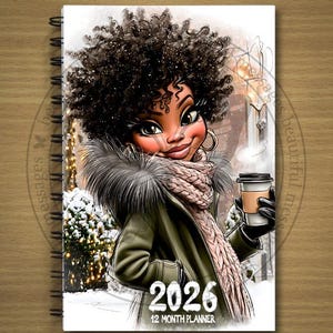 May include: A spiral-bound 2026 12-month planner featuring a cartoon illustration of a woman in a winter coat and scarf, holding a coffee cup. The cover has a snowy winter scene background with the year 2026 prominently displayed.