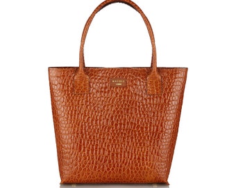 May include: A brown leather tote bag with a crocodile embossed pattern. The bag has a gold logo that says "MARBLE" on the front.