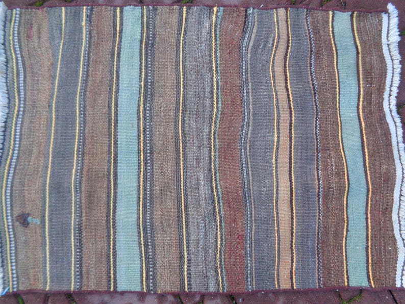 May include: A striped rug with a variety of colors, including brown, blue, and yellow. The rug has a fringed edge.