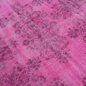 May include: A round pink rug with a faded floral pattern in a darker shade of pink.