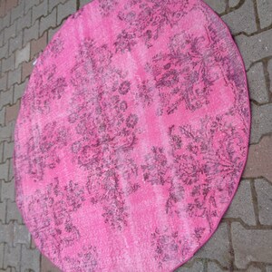May include: A pink round rug with a floral pattern. The rug has a faded look, giving it a vintage feel.
