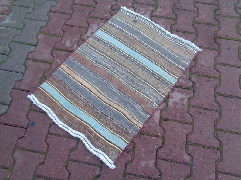 May include: A striped rug with a white fringe. The rug has shades of brown, blue, and beige.