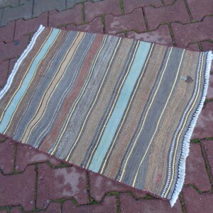 May include: A striped rug with a fringe border. The rug has a variety of colors, including brown, beige, blue, and white.