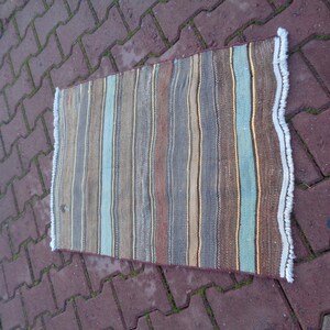 May include: A striped rug with a fringe border. The rug has brown, blue, and beige stripes.