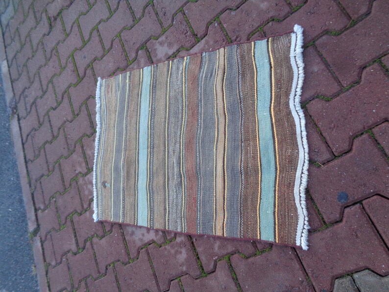 May include: A striped rug with a fringe border. The rug has brown, blue, and beige stripes.