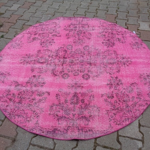 May include: A round pink rug with a faded floral pattern in a darker shade of pink.