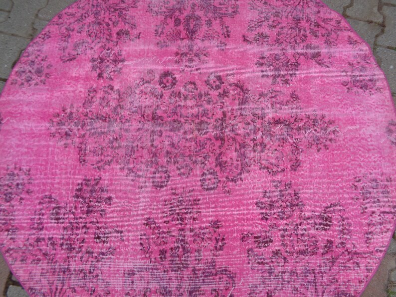 May include: A pink round rug with a faded floral pattern in a darker shade of pink.