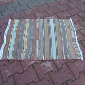 May include: A striped rug with a white fringe. The rug has stripes of brown, blue, yellow, and gray.